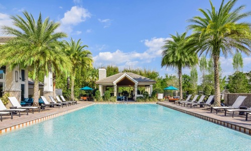 a pool with lounge chairs and umbrellas by a building