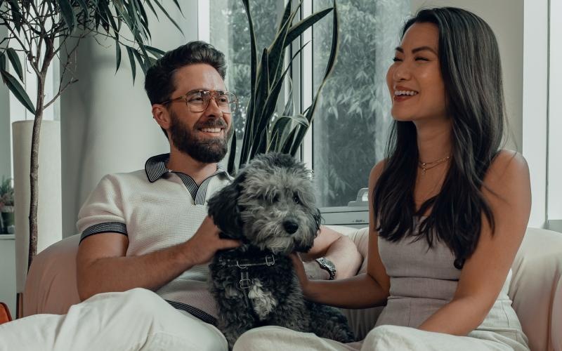 a man and woman sitting on a couch with a dog