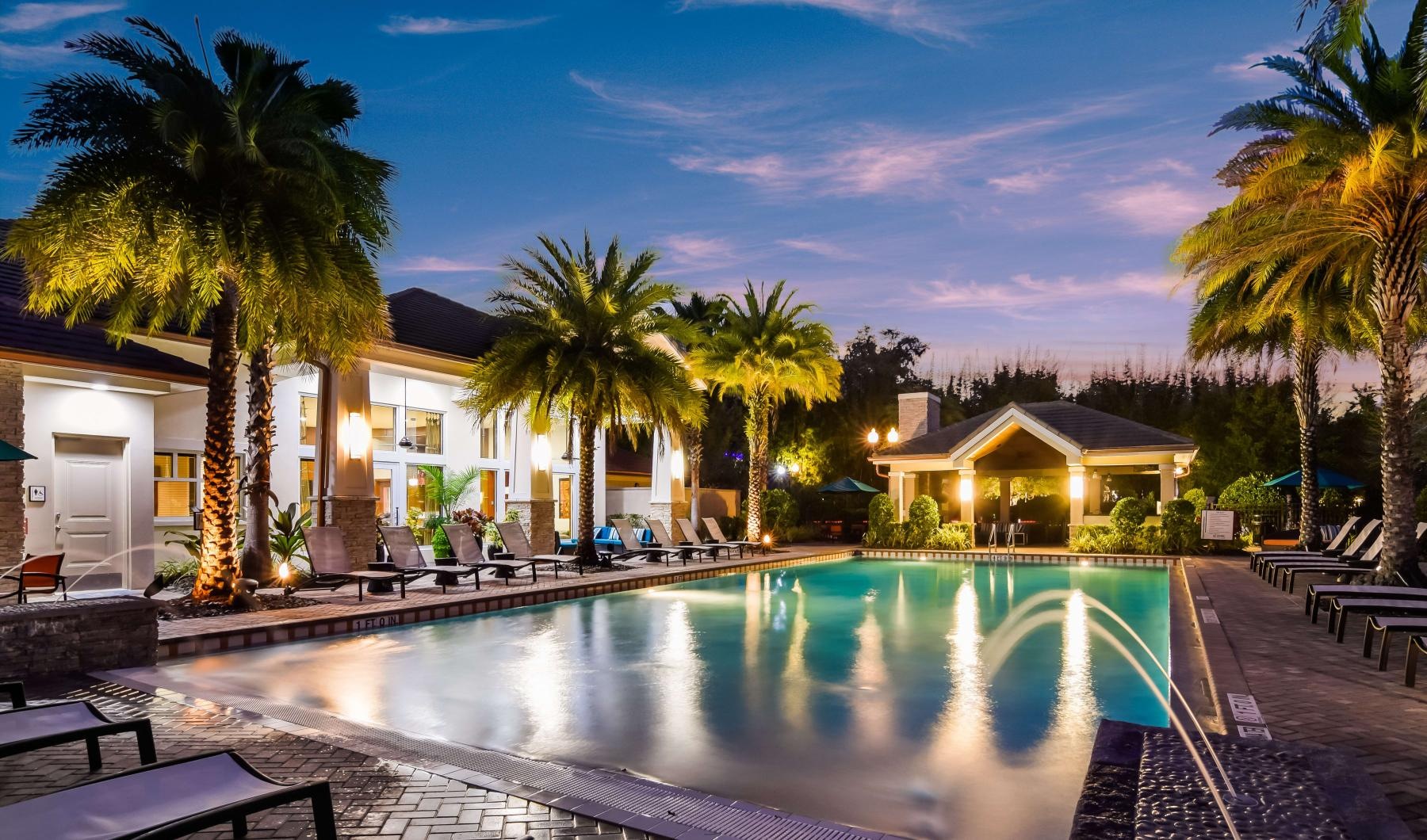 a pool with palm trees and a building in the background